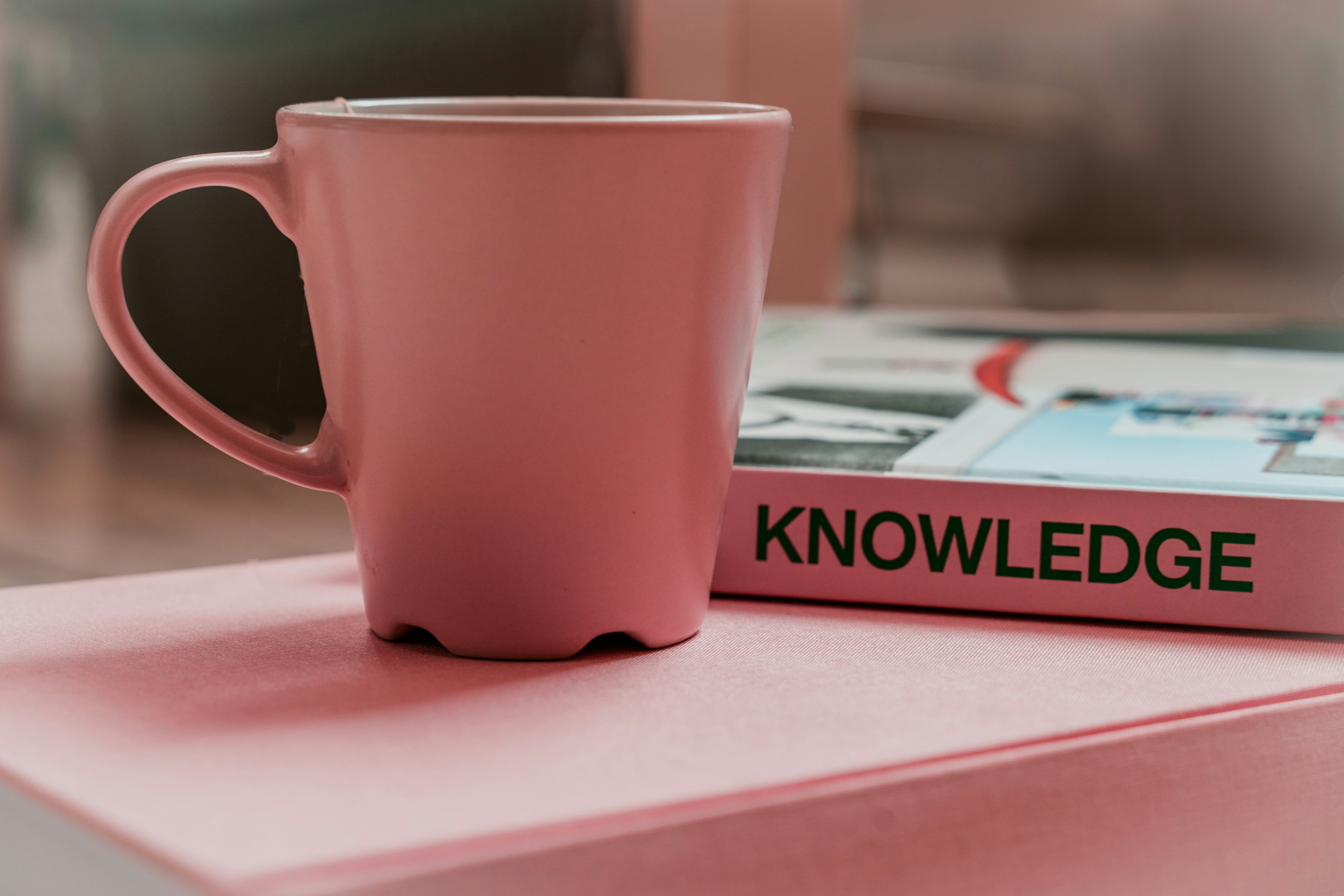 Book entitled "Knowledge" alongside a pink mug
